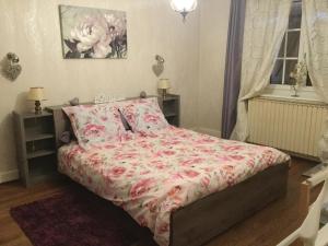 1 dormitorio con 1 cama con colcha rosada de flores en Gîte du Moulin, en Ingersheim
