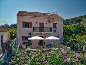 un bâtiment avec deux parasols devant lui dans l'établissement Villa Romantza, à Fiskardho