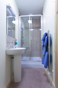 uma casa de banho com um lavatório e um chuveiro com toalhas azuis em Seaview John O Groats Hotel em John O Groats