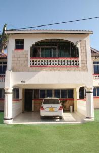 une voiture blanche garée devant un bâtiment dans l'établissement Lucky Sea Breeze Villa, à Mombasa