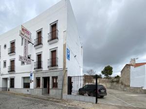 un edificio blanco con un coche aparcado delante de él en Hotel El Volao, en Villanueva de Córdoba