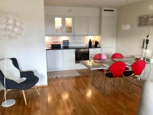 a kitchen with a table and red chairs in a room at Sjønær leilighet med gangavstand til strand i Larvik in Larvik