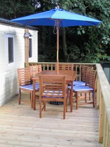 a wooden table and chairs with an umbrella on a deck at Cornwall Caravan Holidays in Saint Minver