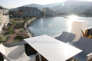 a table and chairs on a balcony with a view of a river at Hotel U Viveiro in Viveiro