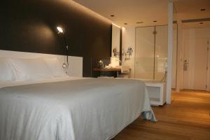 a bedroom with a white bed and a shower at Hotel U Viveiro in Viveiro