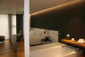 Hotel U Viveiro في فيفييرو: حمام به سرير وحوض استحمام