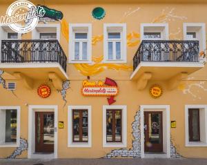 Un bâtiment jaune avec quelques panneaux. dans l'établissement Hotel Marienplatz Podgorica, à Podgorica