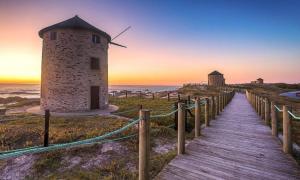 a wooden boardwalk leading to a windmill on the beach at Beach House - Between Porto and Viana do Castelo in Esposende
