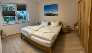 um quarto com uma cama grande com lençóis brancos e almofadas em Fewo Barth em Barth
