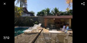 un patio con mesa y sillas junto a una piscina en Casa na Praia c/Piscina e Churrasqueira, en Itanhaém