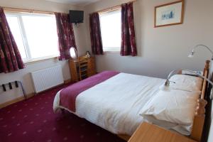 a bedroom with a bed and two windows at Seaview John O Groats Hotel in John O Groats