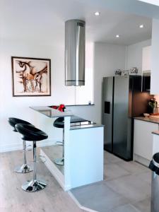 a kitchen with a counter with stools and a refrigerator at LUXE EIFFEL TOWER AND SEINE RIVER in Paris