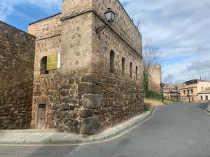 an old stone building with a street next to it at Alda Apartamentos Muralla de Toledo in Toledo