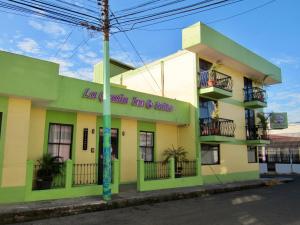 un edificio amarillo y verde con un cartel en él en Hotel La Guaria Inn & Suites, en Alajuela