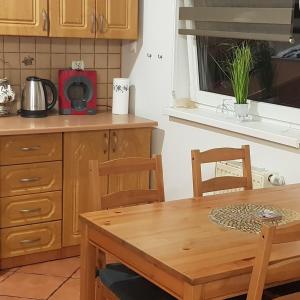 eine Küche mit einem Holztisch sowie einem Tisch und Stühlen in der Unterkunft Apartament Komorniki in Komorniki