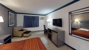 a hotel room with a bedroom with a bed and a mirror at Waconia Inn and Suites in Waconia