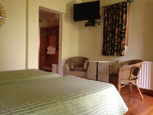 a bedroom with a bed and two chairs and a television at Los Abetos B&B 1 in El Bolsón