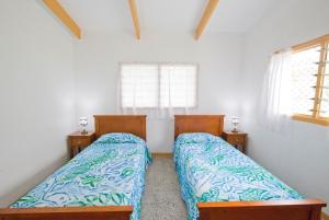 two beds in a room with two windows at Muri Homeland Villa in Rarotonga
