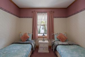 two twin beds in a room with a window at Settlers Cottage Motel in Arrowtown