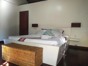 a bedroom with a large white bed with a basket on it at Villa Kalachuchi V.K in Puerto Princesa City