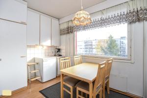 a kitchen with a wooden table and chairs and a window at Next to City Center, Beside Bus and Train Station, Safe and Cozy Place in Oulu