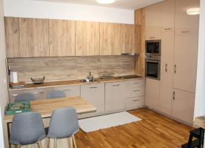 a kitchen with wooden cabinets and a wooden table and chairs at Bright, modern & cozy apartment in Tuzla