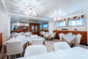 a dining room with white tables and white chairs at Tom Hotel in Vladivostok