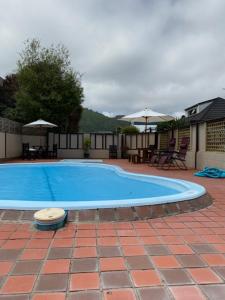 a large blue swimming pool on a brick patio at Arikilodge in Waikanae