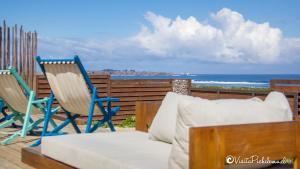 a patio with two chairs and a couch and the ocean at SaldeMar Playa Hermosa in Pichilemu
