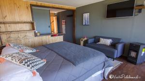 a bedroom with a bed and a chair and a television at SaldeMar Playa Hermosa in Pichilemu