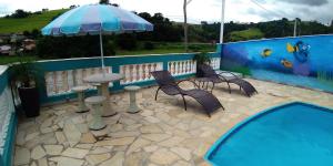 un patio avec une table, des chaises et un parasol dans l'établissement Chácara Oliveira, à Socorro