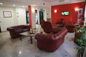 une salle d'attente avec des meubles en cuir brun et des murs rouges dans l'établissement iH Hotels Milano ApartHotel Argonne Park, à Milan