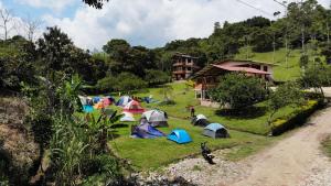 um grupo de pessoas acampando em um campo com tendas em Hospedaje y Camping Buena Vista em San Agustín