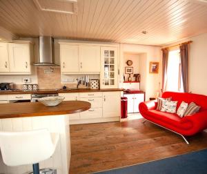 a kitchen with a red couch and a red chair at Tabs Cottage in Fowey