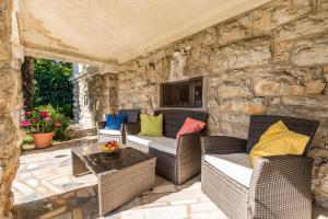 patio con pareti in pietra, tavolo e sedie in vimini di Apartment Carolina a Opatija