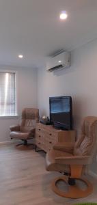 a living room with two chairs and a flat screen tv at Thistle B&B in Napier