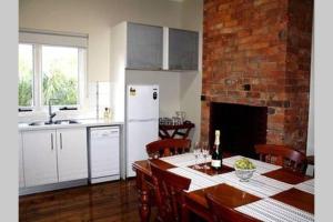a kitchen with a table and a brick wall at Kenmaur Cottage in Kyneton