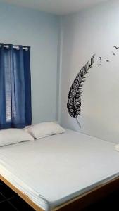 a bedroom with a bed with a feather stencil on the wall at Nong Or Blue House Resort in Sukhothai