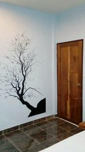 a tree mural on a wall next to a door at Nong Or Blue House Resort in Sukhothai
