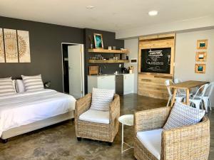 a bedroom with a bed and two chairs and a kitchen at Lower Point Surf Studio 2 in Jeffreys Bay +13 photos