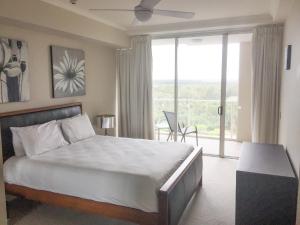 a bedroom with a bed and a large window at Pelican Waters Resort in Caloundra +9 photos