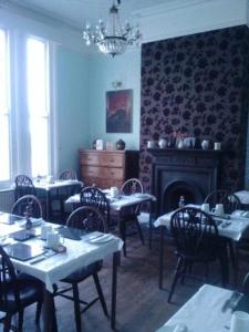 a dining room with tables and chairs and a fireplace at Seahaven House in Ryde