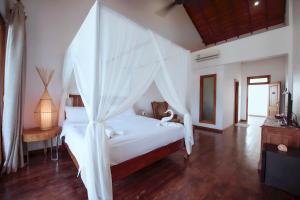 a bedroom with a white bed with a canopy at Cardamon Hotel Nilaveli in Nilaveli