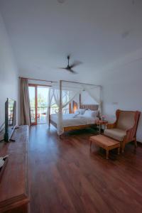 a bedroom with a bed and a couch and a chair at Cardamon Hotel Nilaveli in Nilaveli