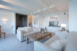 a living room with couches and a table and a tv at The Alpine Way Queenstown in Queenstown
