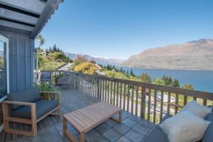 a porch with a table and a chair and a lake at The Alpine Way Queenstown in Queenstown