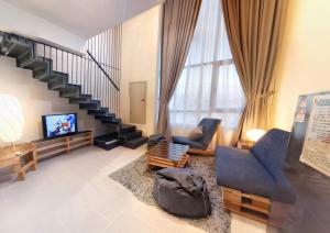 a living room with two chairs and a television at Tamarind Suites by BeeStay Management in Cyberjaya