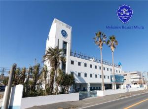 un edificio bianco con una torre dell'orologio con palme di Mykonos Resort Miura / Vacation STAY 62208 a Yokosuka