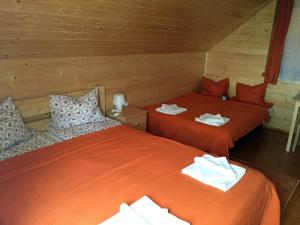 dwa łóżka w pokoju z pomarańczową pościelą w obiekcie Nimfa Apartments w mieście Păuleni-Ciuc
