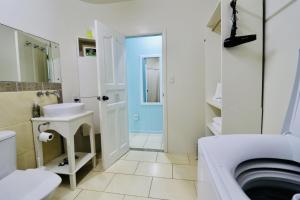 ein weißes Bad mit einem Waschbecken und einem WC in der Unterkunft ShineAwayHomes -AC Beachfront RAROTONGA in Matavera